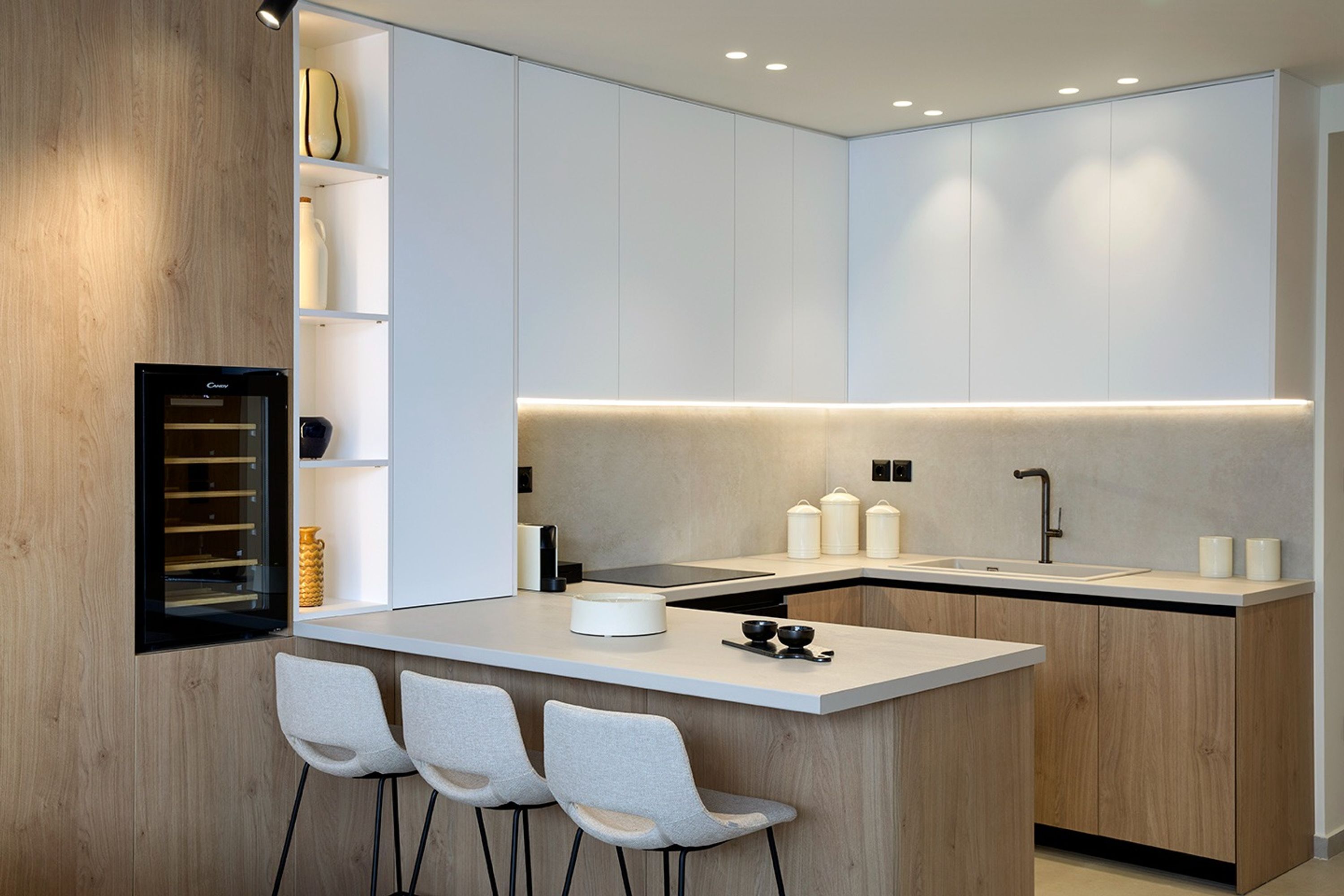 A modern kitchen with a central island, bar stools, and built-in cabinetry.