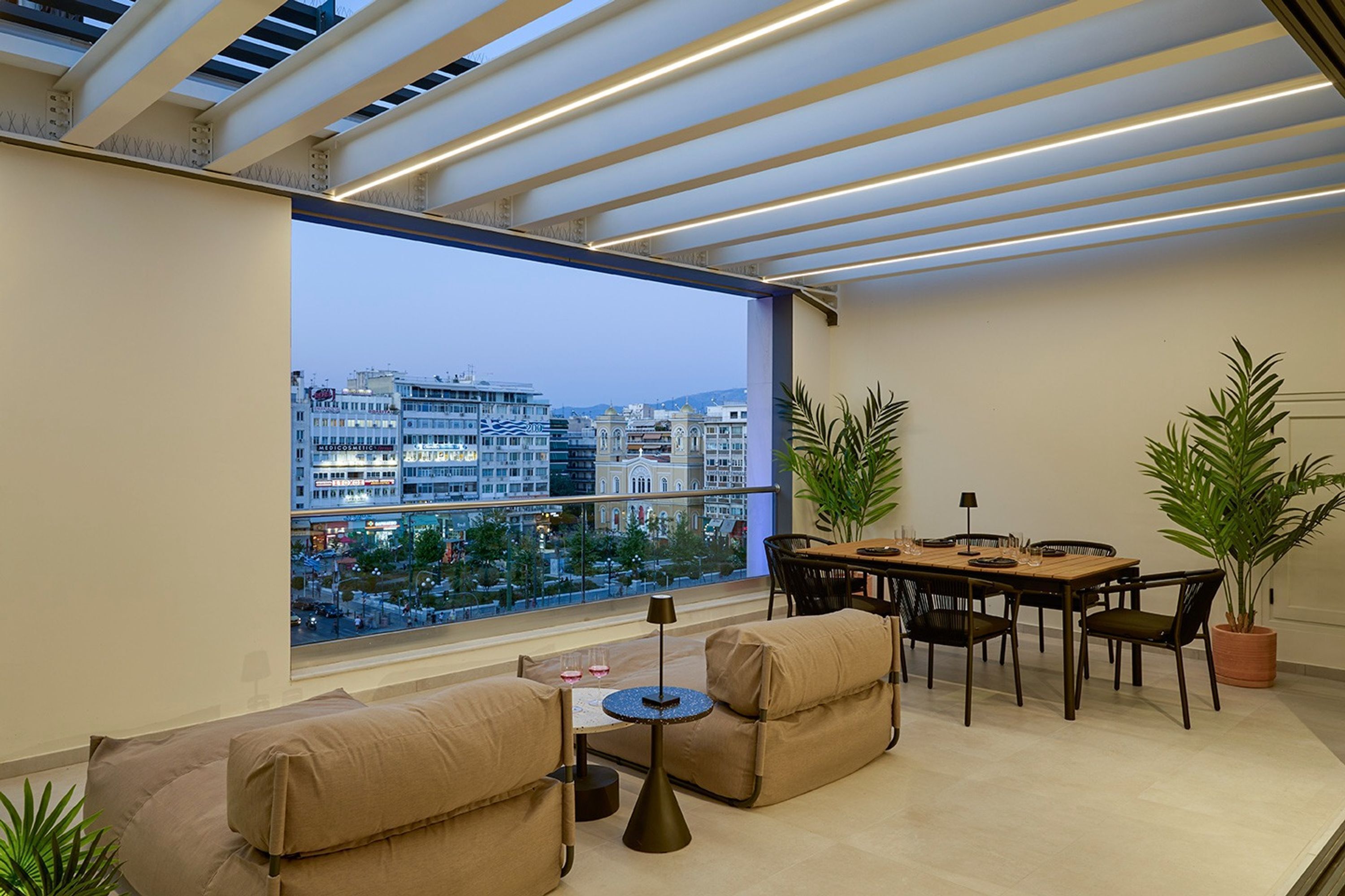 A modern living room with a large window, a dining area, and two sofas.