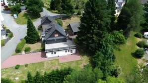 A large, multi-story house with a prominent gabled roof, surrounded by lush greenery and a paved driveway. - Apartment 'Gellinghausen' with Shared Terrace, Private Garden and Wi-Fi (Schmallenberg)
