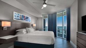 Ein modernes Hotelzimmer mit einem großen Bett, einem Deckenventilator, einem Fernseher und einem Balkon mit Meerblick.