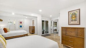 A bedroom with two beds, a wooden dresser, and a large mirror.