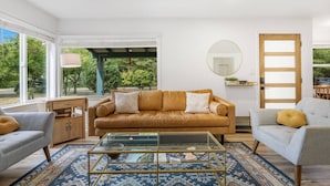 A modern living room with a leather sofa, a glass coffee table, and a blue patterned rug.