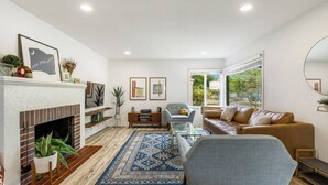 A modern living room with a fireplace, a sofa, a coffee table, and a large window.
