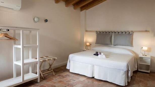 A bedroom with a bed, bedside tables, a wardrobe, and a hanging rack. - Borgodieci Camere e Colazione (Bibbiano)
