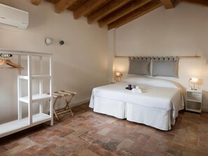 Un dormitorio con cama, mesitas de noche, armario y perchero.