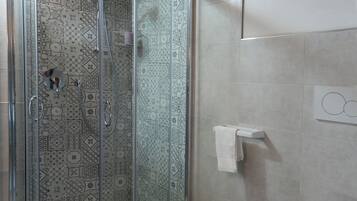 Un baño con cabina de ducha, bidé e inodoro.