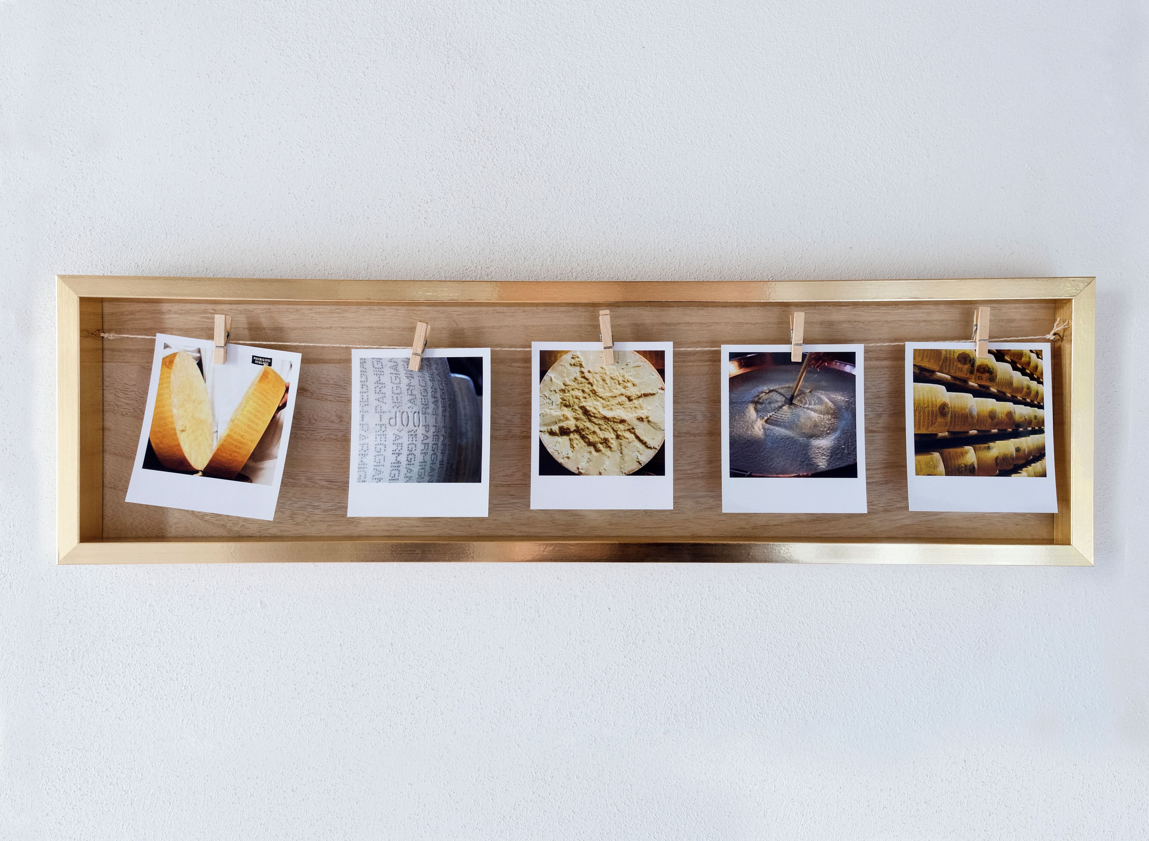 Un vassoio di legno con cinque foto Polaroid appese a una parete.