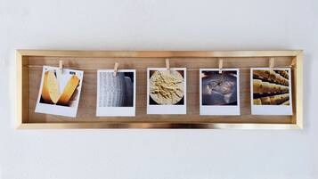 Un vassoio di legno con cinque foto Polaroid appese a una parete.