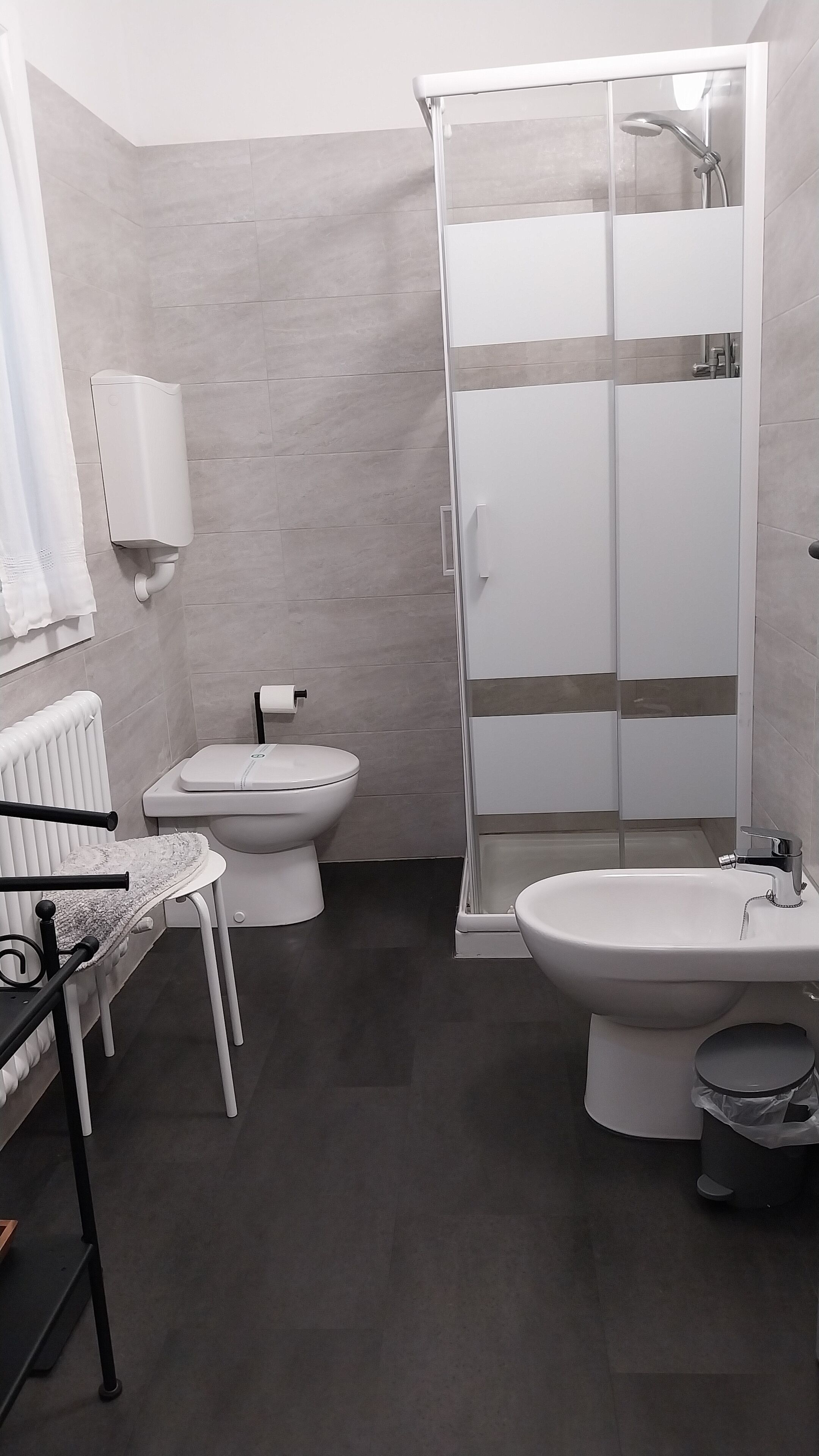 Une salle de bain moderne équipée d’une douche, de toilettes, d’un bidet et d’un lavabo.