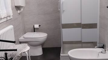 Une salle de bain moderne équipée d’une douche, de toilettes, d’un bidet et d’un lavabo.