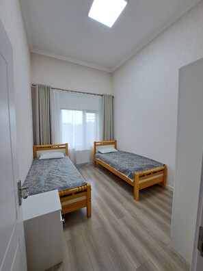 A room with two wooden beds, a white wardrobe, and a skylight.