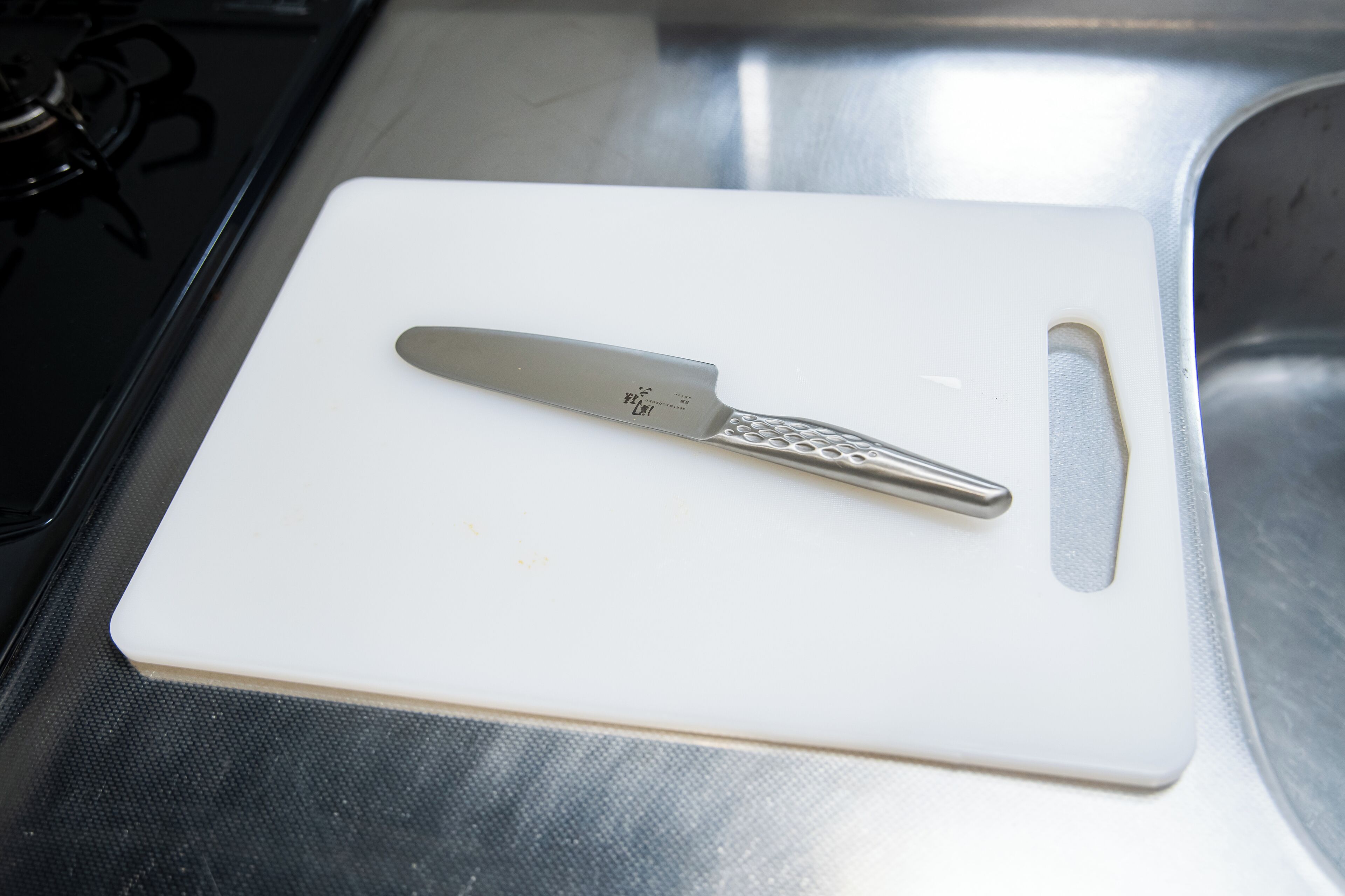 A kitchen with a white cutting board and a knife on it.