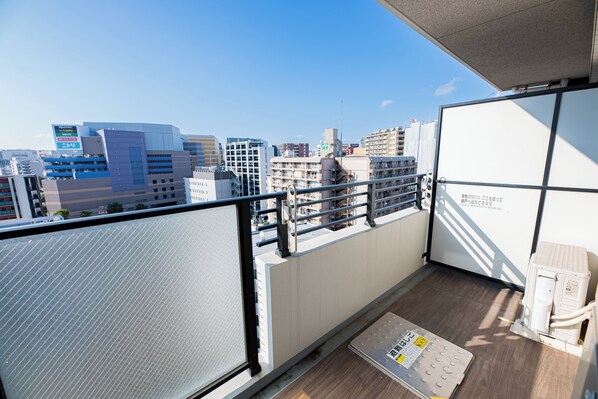 A balcony with a city view, metal railing, and a wooden floor. - SPAZIO 1 Canal Hakata (Fukuoka)
