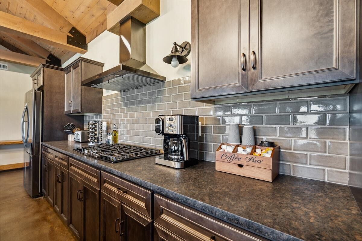 A kitchen with dark wood cabinets, a gas stove, a coffee maker, and a coffee bar sign.