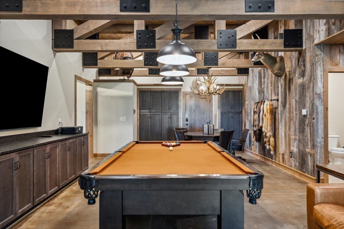 A pool table in a room with wooden beams and a chandelier.