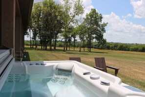 A hot tub with a view of a grassy field and trees.