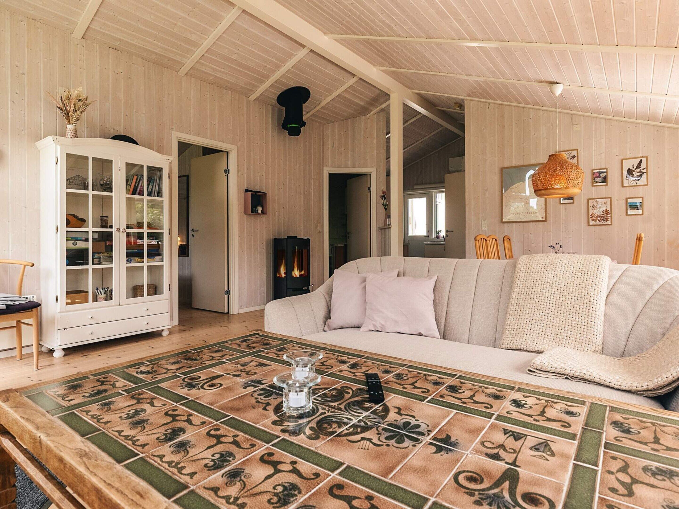 A cozy living room with a wooden floor, a sofa, a cabinet with glass doors, and a fireplace.