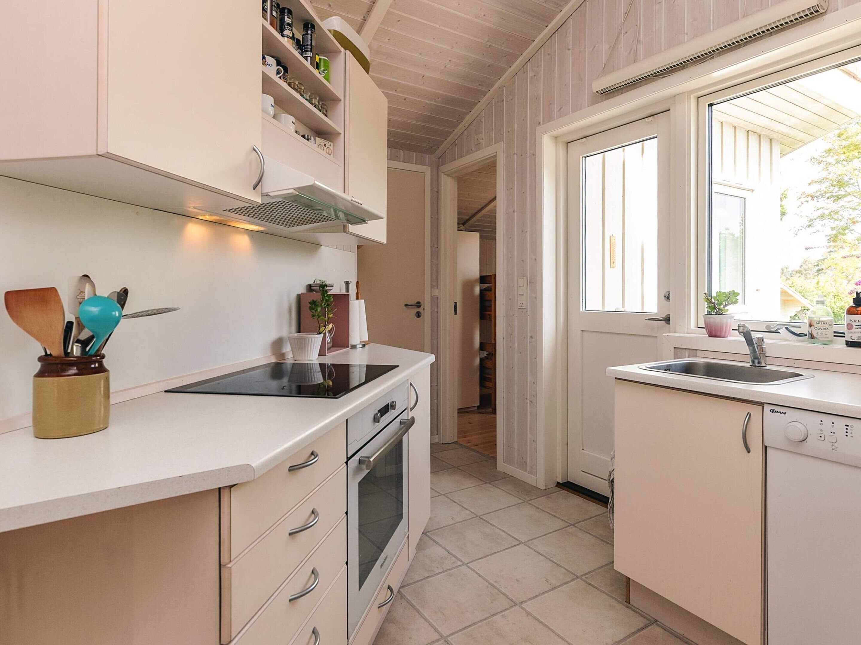 Una cucina con piano cottura, forno e lavello. Si vede una finestra con vista sull'esterno.