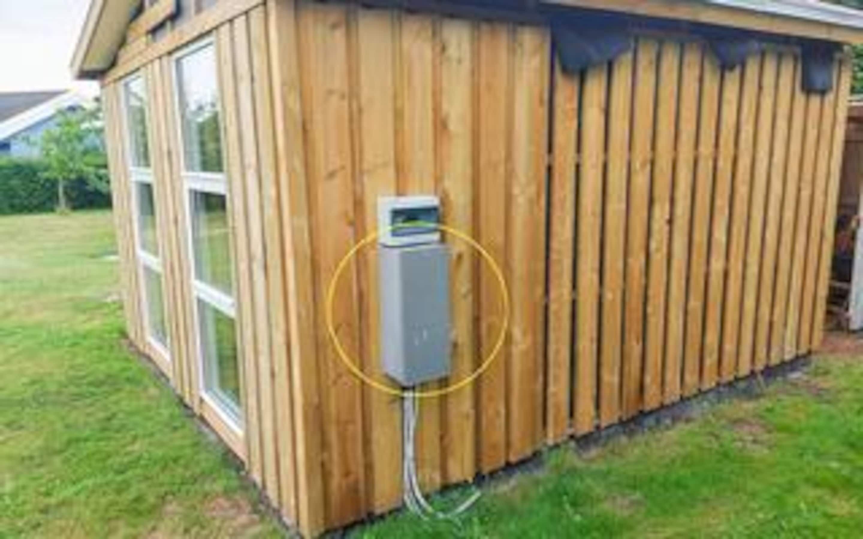 A wooden building with a window and an electrical box mounted on the side.