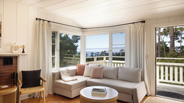 A cozy living room with a sectional sofa, a round coffee table, and a fireplace. - Charming Carmel Cottage Ocean & Mntn View Walk DT (Carmel)