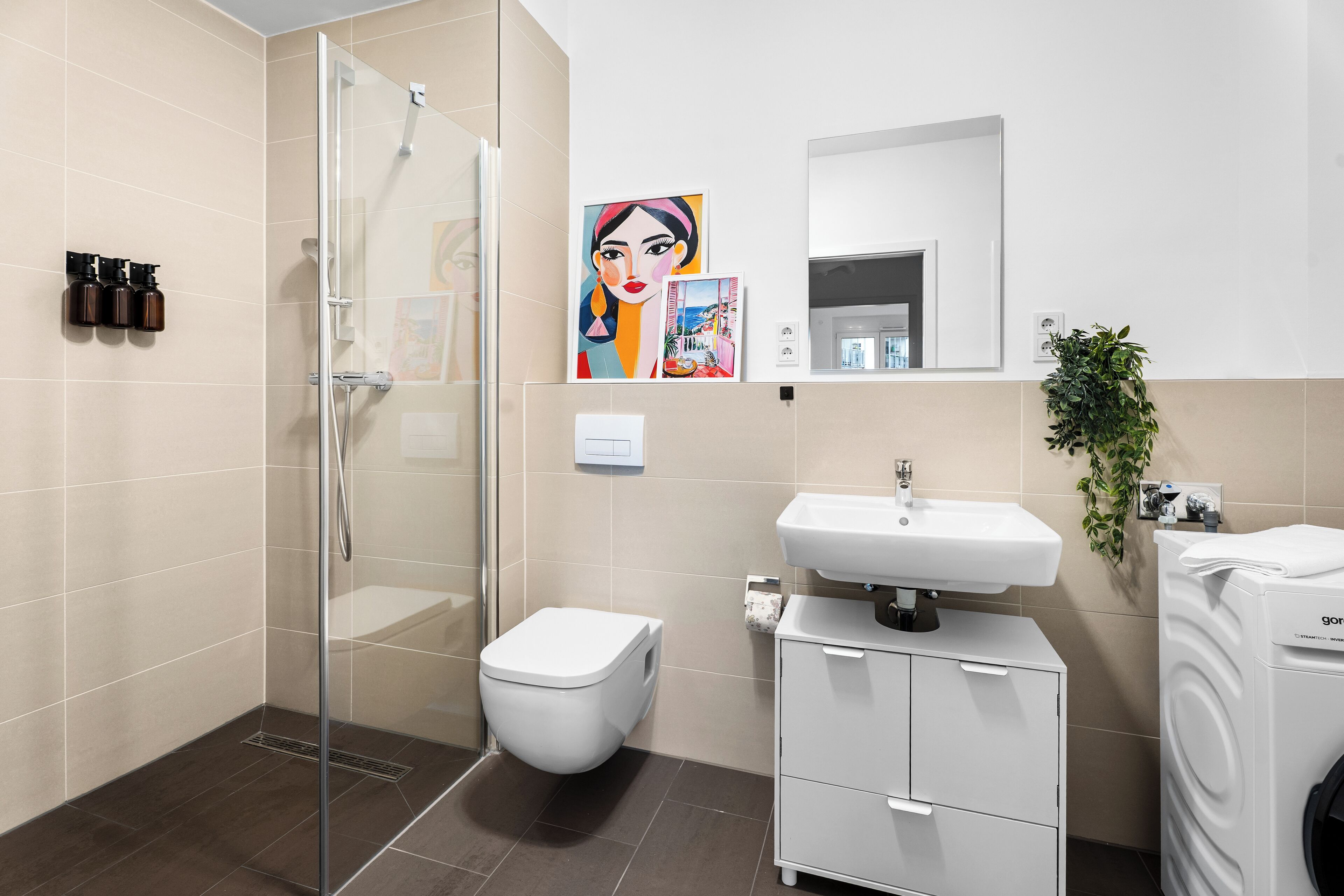 Un bagno moderno con box doccia in vetro, un water, un lavabo e un piccolo armadietto.