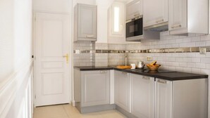 A modern kitchen with white cabinets, a black countertop, and a stainless steel oven. - Practical Apartment for 3 people in charming Paris (Paris)