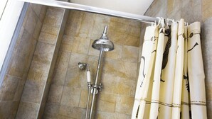 A shower with a handheld showerhead and a wall-mounted faucet, a white shower curtain with a bird pattern, and stone tiles on the walls. - Practical Apartment for 3 people in charming Paris (Paris)