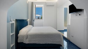 Un dormitorio con cama, ventana, televisión y balcón.