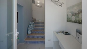 A staircase with patterned steps, a wall-mounted light fixture, and a painting. - Room 'Camera Furore Sea View' with Sea View, Wi-Fi and Air Conditioning (Furore)