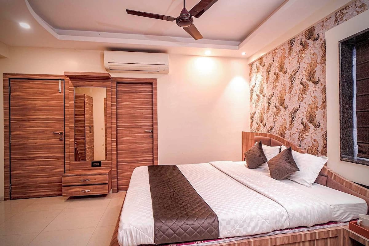 A bedroom with a bed, wooden wardrobe, and a ceiling fan.