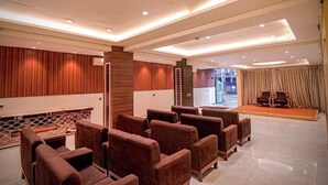 A spacious lobby with a seating area, a stage, and a modern design. - Roli Residency (Barasat)