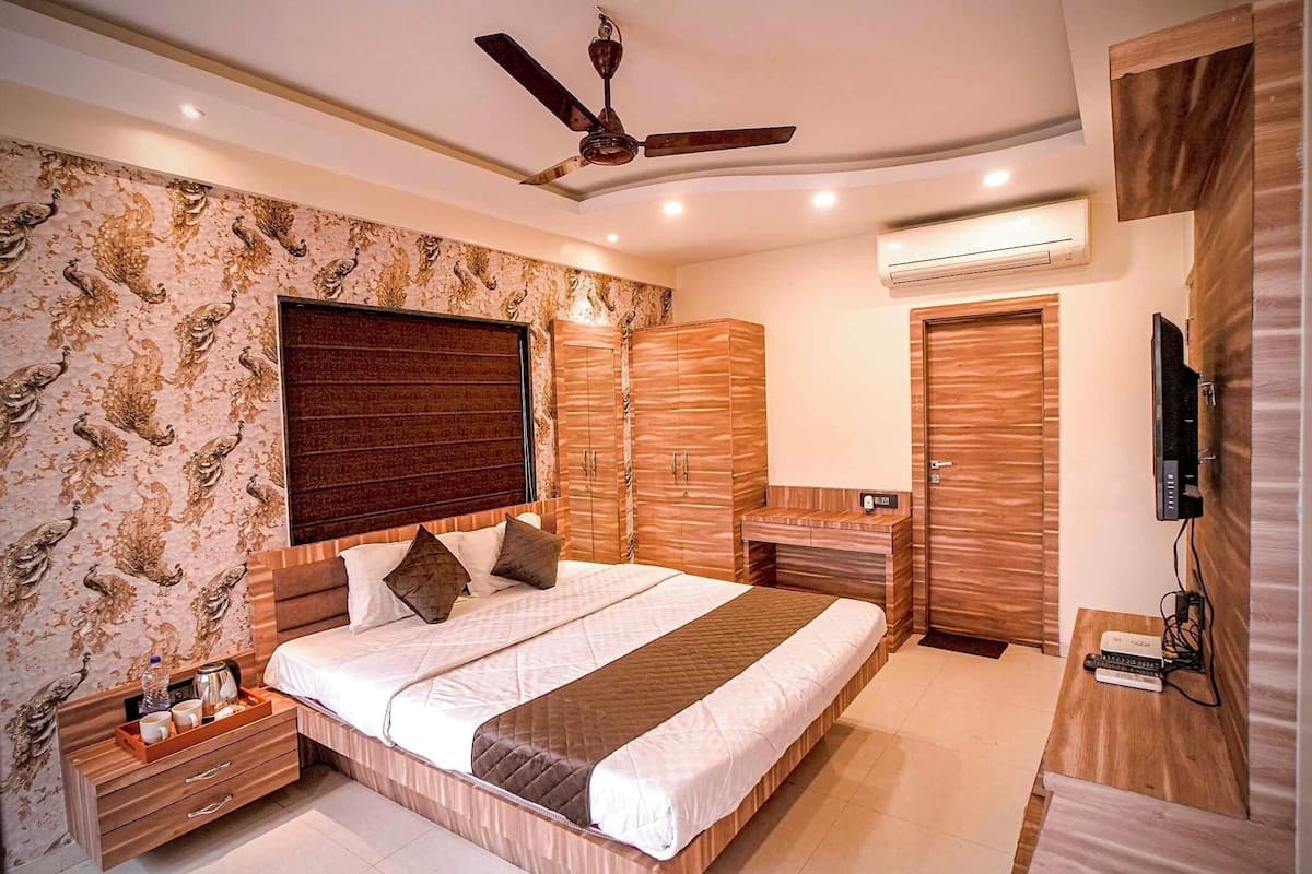 A modern bedroom with a large bed, wooden wardrobe, and a ceiling fan.