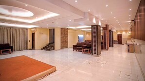 A spacious hotel lobby with a large seating area, a staircase, and a reception desk. - Roli Residency (Barasat)