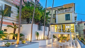 Une cour avec des espaces de détente en plein air, des palmiers et un bâtiment doté de balcons.