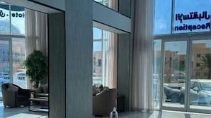 A modern lobby with a central water feature, large windows, and seating areas. - Seven Garden Hotel - Airport (Taif)