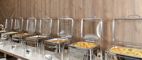 A buffet line with various food containers and serving utensils.