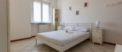 A bedroom with a bed, bedside tables, a window, and a radiator.