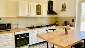 A kitchen with white cabinets, a black stove, and a microwave. - VILLA COSY (fumel)