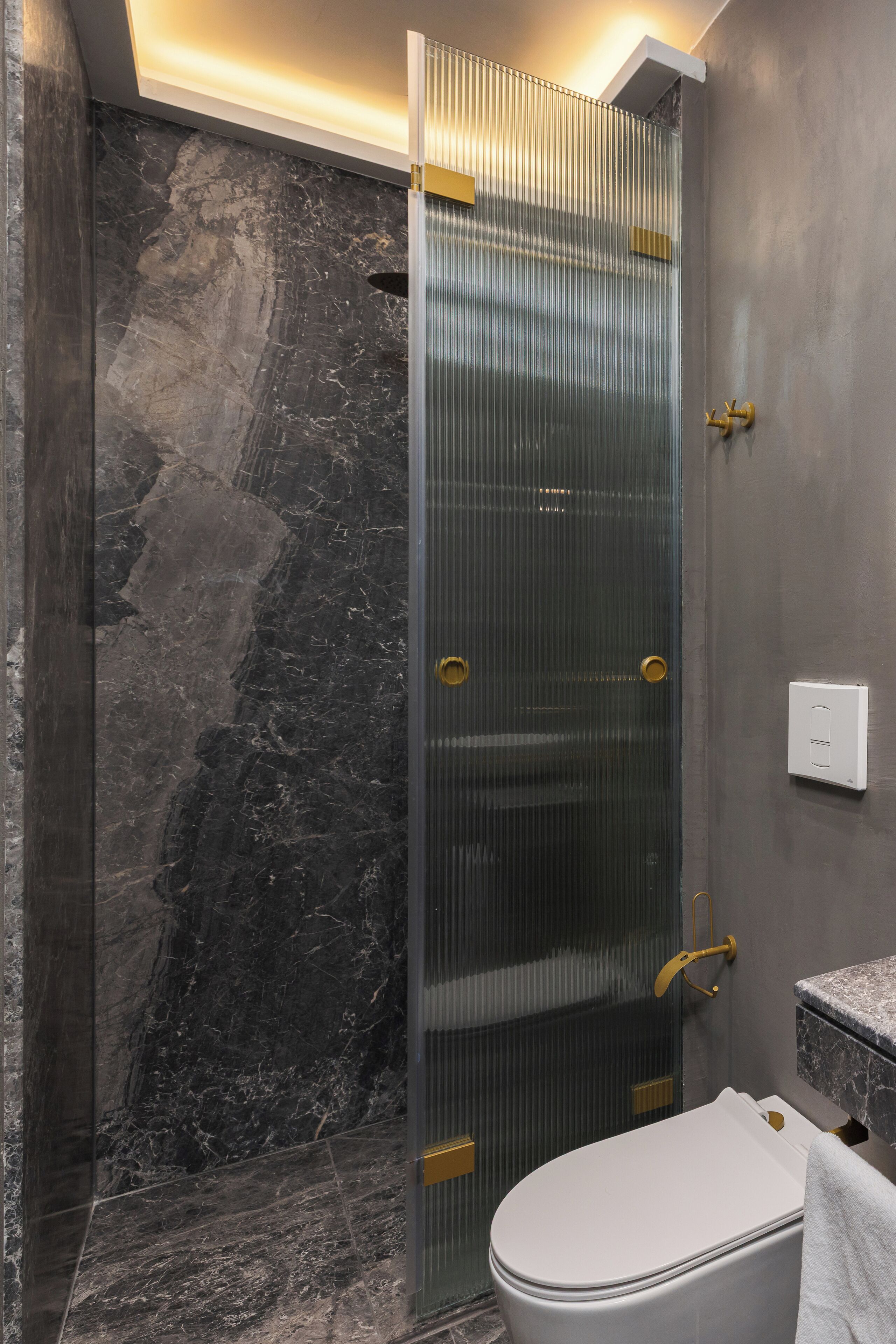 A modern bathroom with a glass shower enclosure, a marble-tiled floor, and a white toilet.