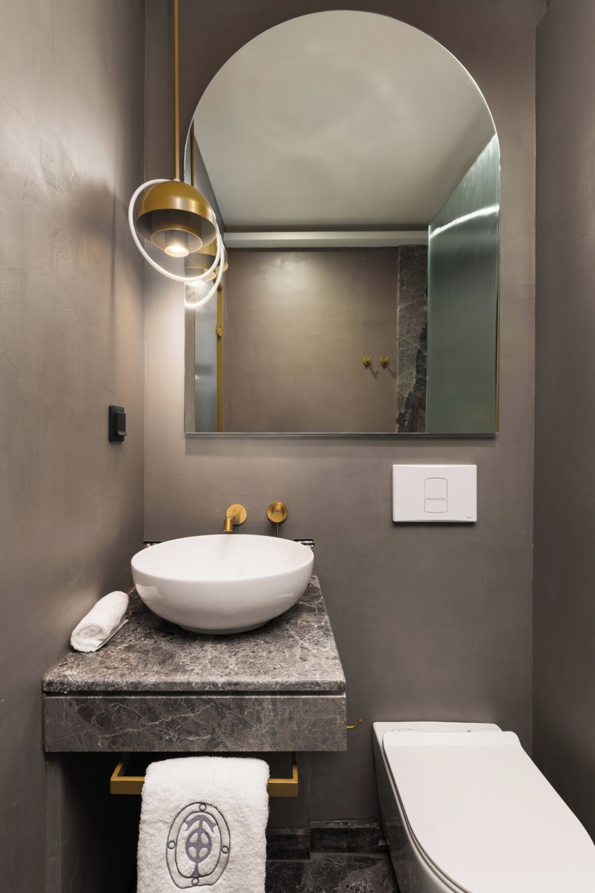 Ett modernt badrum med ett runt handfat, en spegel och en toalett.