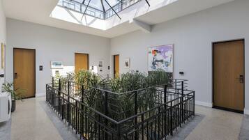 A modern interior with a central plant area, skylight, and wooden doors.