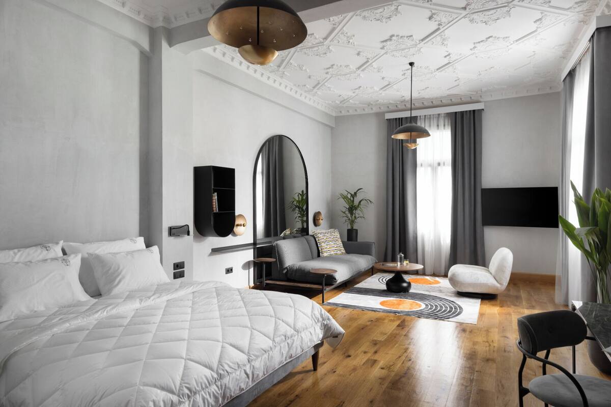 A modern bedroom with a large bed, a sofa, a coffee table, and a TV mounted on the wall.