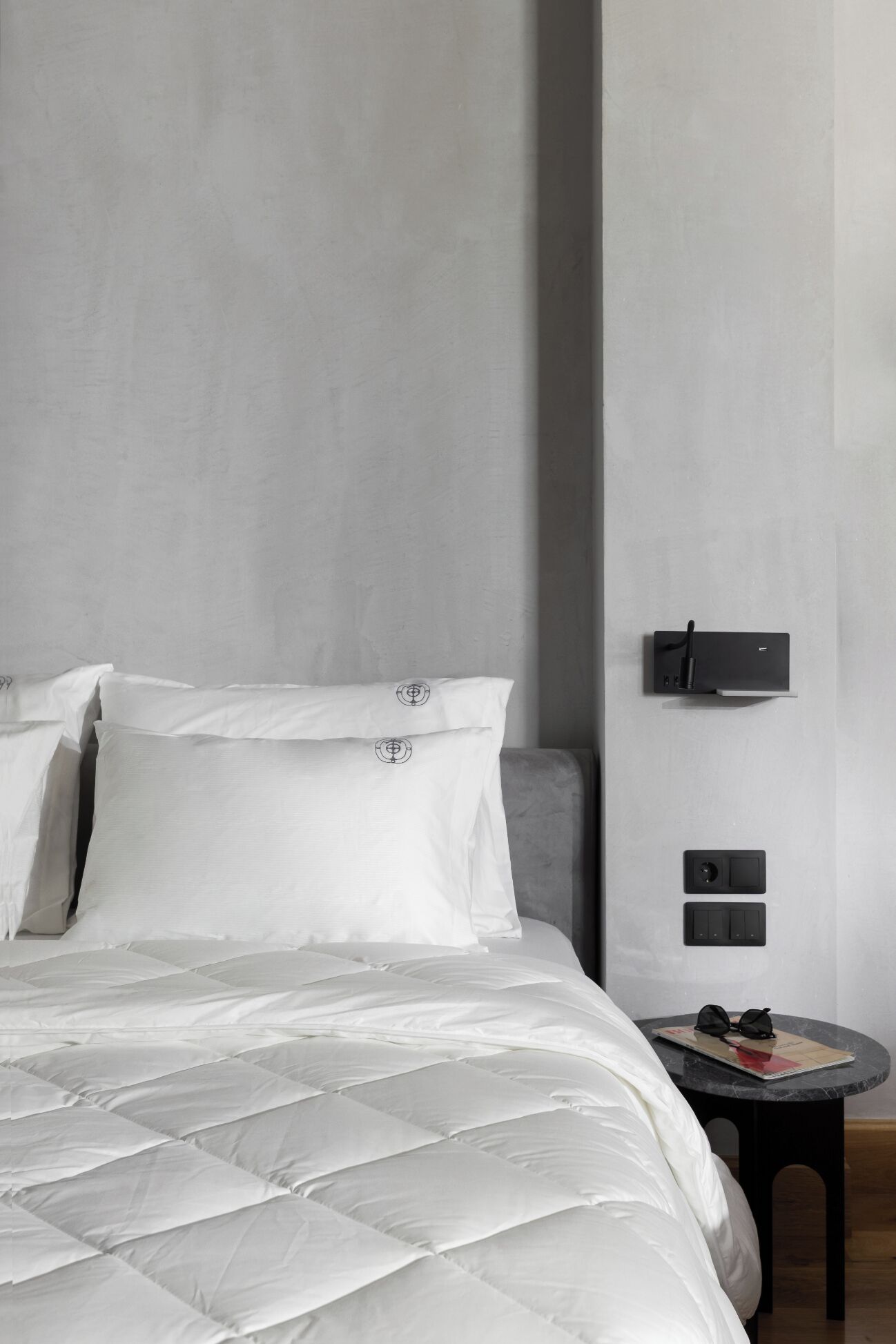 Ein modernes Schlafzimmer mit einem großen Bett, einem kleinen Nachttisch und einer Wandleuchte.