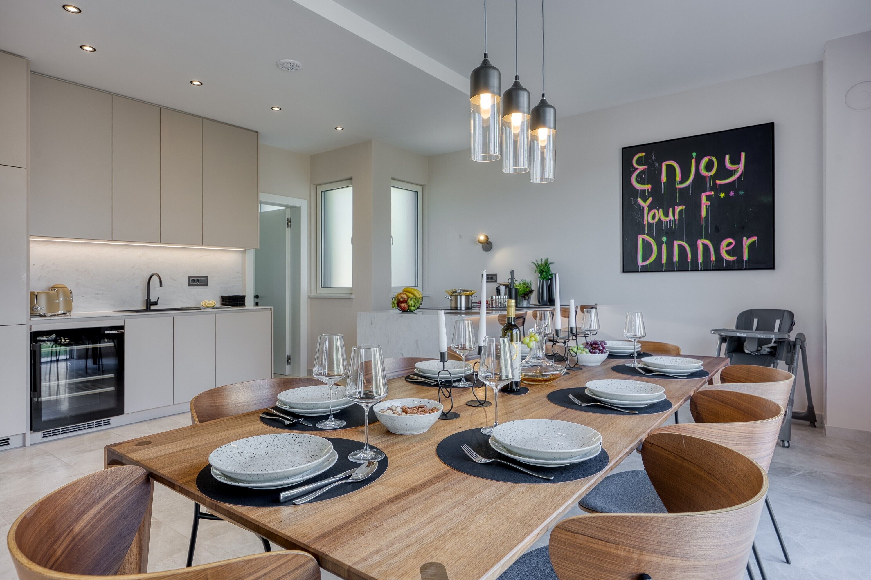 Un comedor moderno con una mesa de madera lista para la cena, rodeada de sillas de madera.