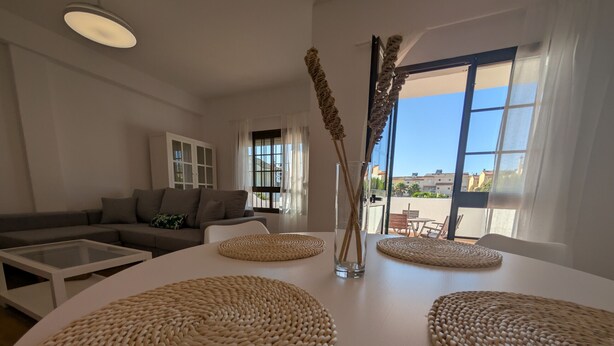 Ein modernes Wohnzimmer mit einem weißen Sofa, einem Glastisch und gewebten Untersetzern auf einem weißen Tisch.