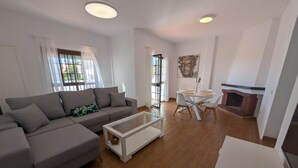 Ein modernes Wohnzimmer mit einem grauen Ecksofa, einem Glastisch und einem Kamin aus Ziegelsteinen.
