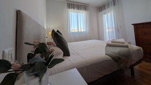 Ein Schlafzimmer mit Bett, Nachttisch und einer Vase mit Blumen.