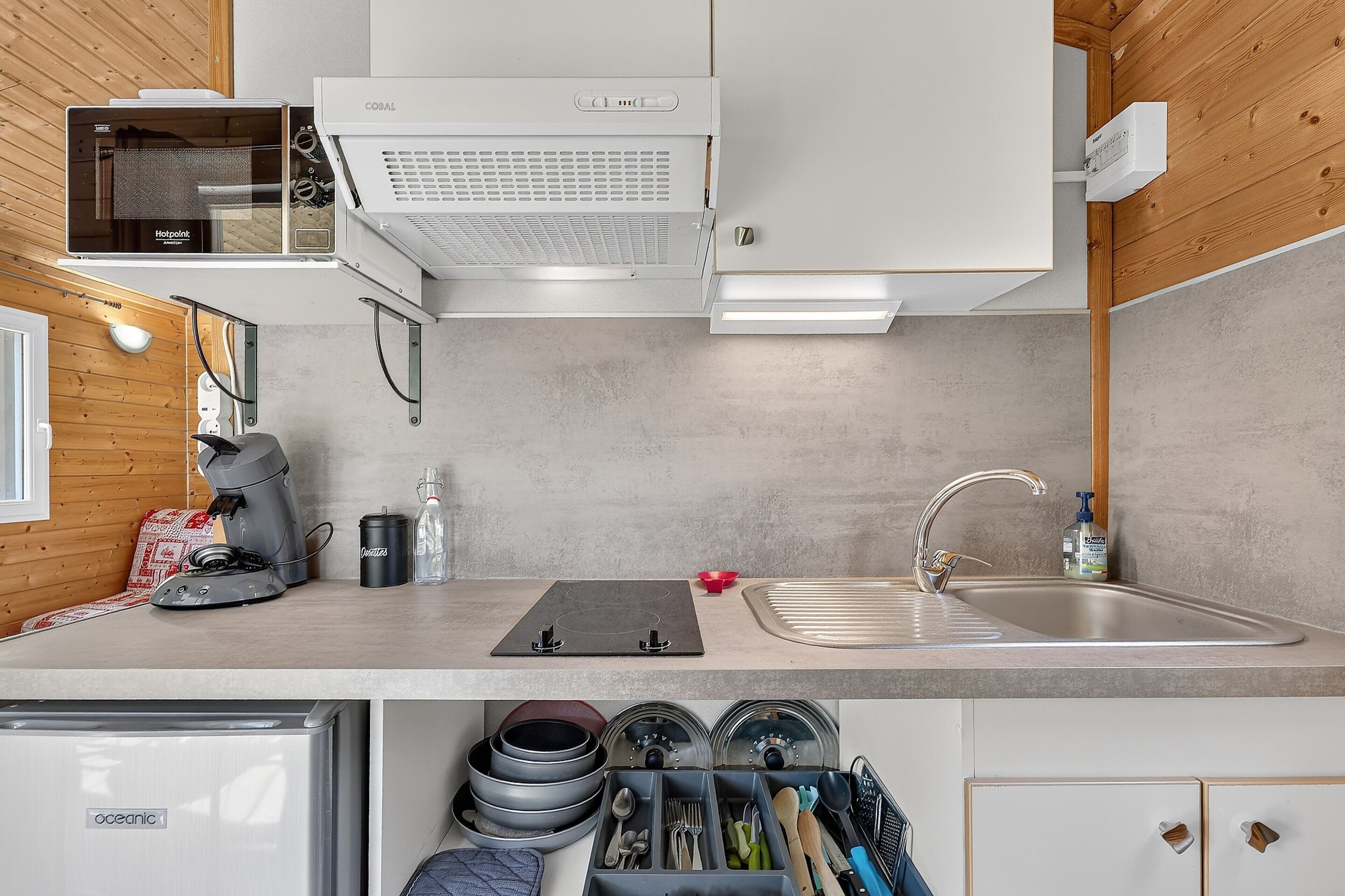 Eine moderne Küche mit Einbauofen, Kaffeemaschine, Spüle und einem kompakten Kühlschrank.