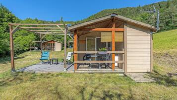 A small wooden cabin with a porch, a table, and chairs.