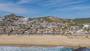 Un pueblo costero con propiedades frente al mar, una playa de arena y un paisaje montañoso.